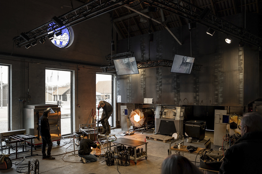 Glassblowers working at Holmegaard Værk museum, illuminated by ERCO LED spotlights.