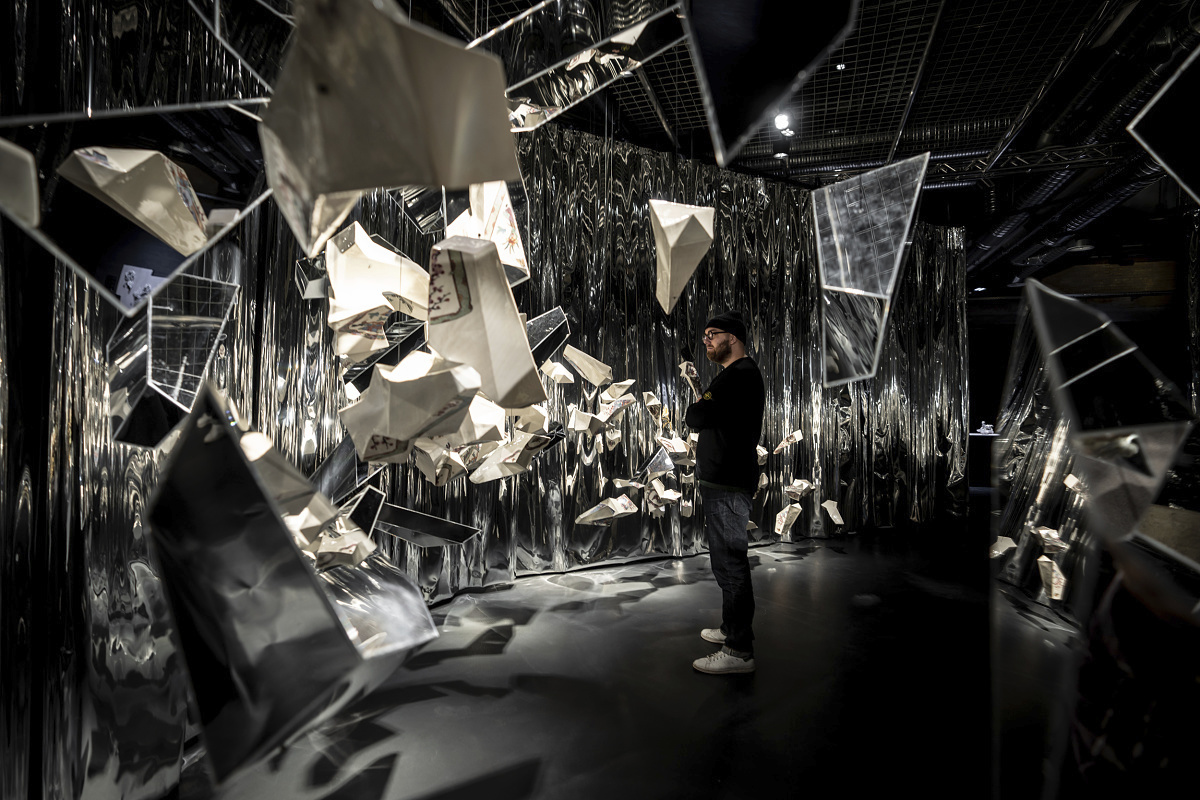 Man views glass art illuminated by ERCO LED spotlights at Holmegaard Værk museum, Denmark.