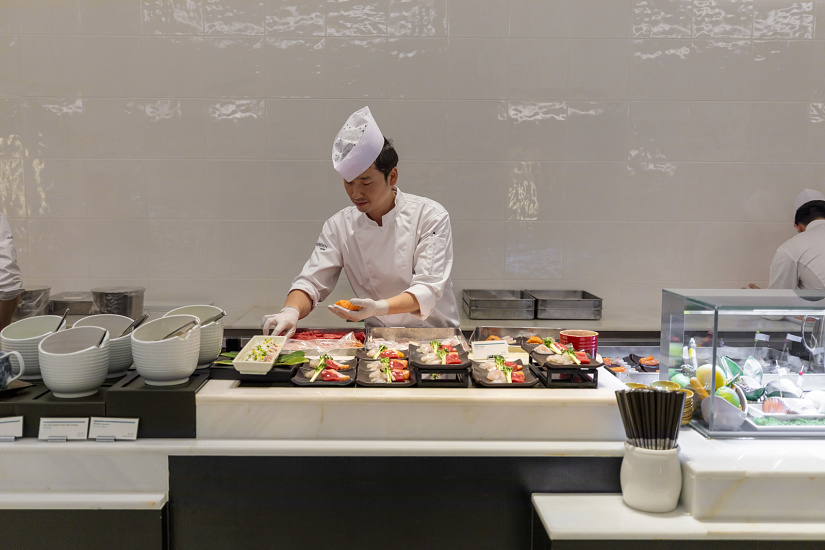 Sushi chef preparing food at Le Méridien Seoul, highlighted by ERCO lighting for hospitality ambiance.
