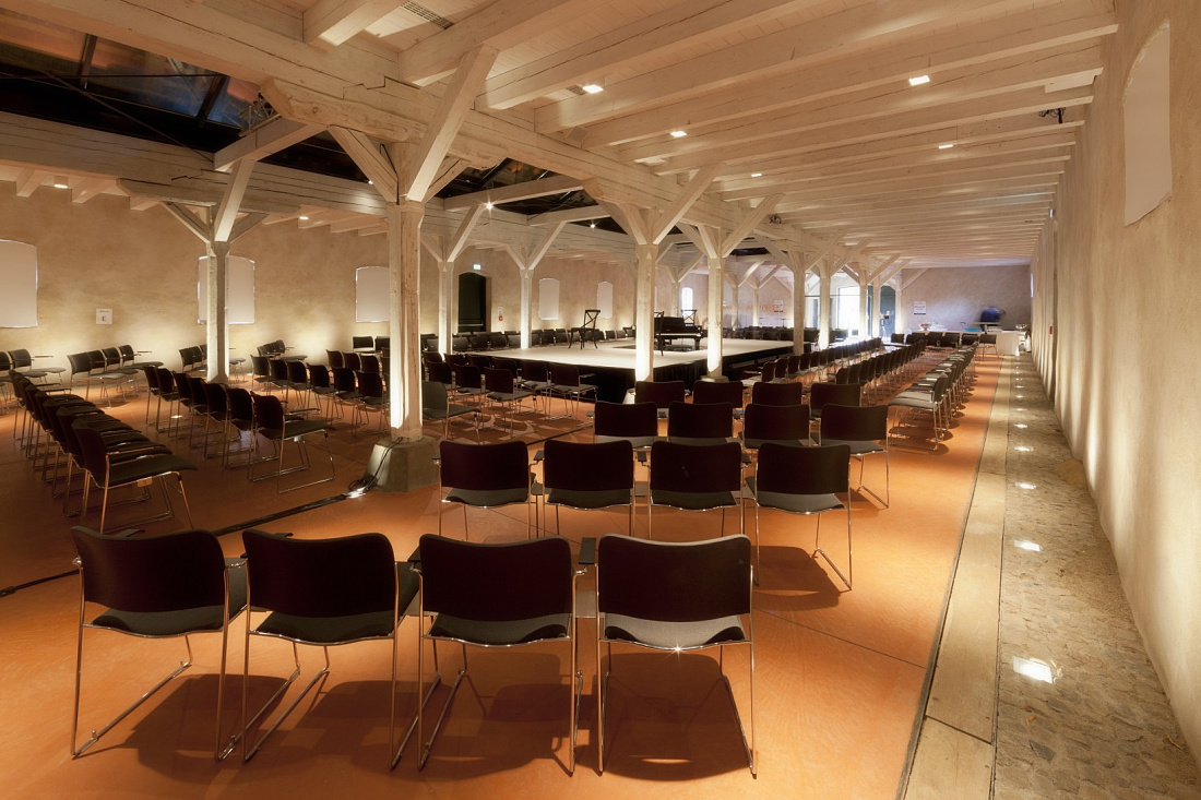 Event space at Hotel Weissenhaus with ERCO lighting and rows of chairs for guests.