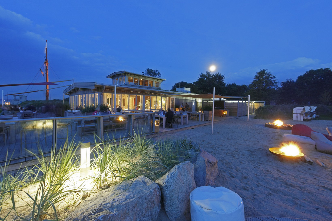 Illuminated Weissenhaus Grand Village Resort & Spa at dusk with outdoor lighting.