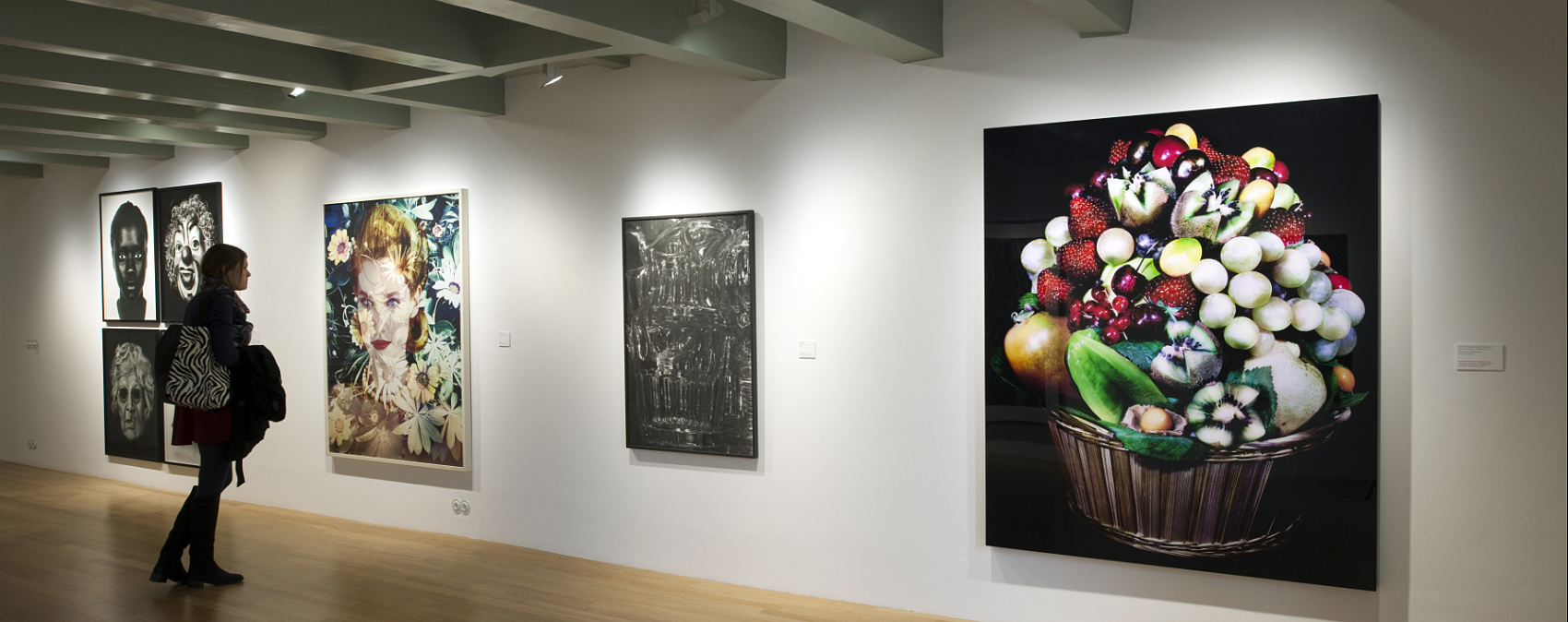 Woman views art illuminated by ERCO LED spotlights at Huis Marseille museum.