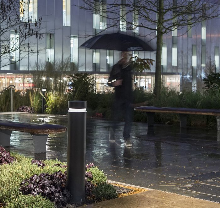 ERCO bollard luminaire illuminating a rainy park path, providing orientation and safety in the dark.