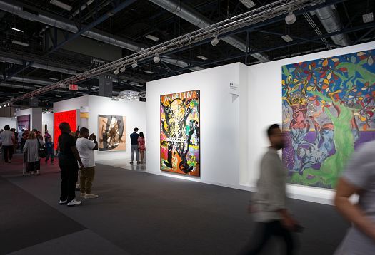 Art Basel Miami illuminated by ERCO: Visitors view paintings under track lighting.