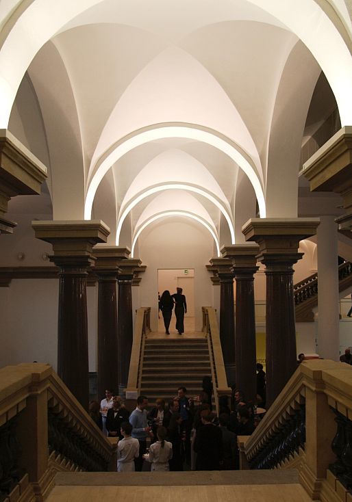 Interior of K21 Art Gallery featuring stairs, columns, and visitors, illuminated by ERCO lighting.