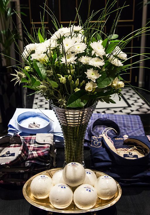 La Martina boutique display: Polo balls and shirts with floral arrangement.