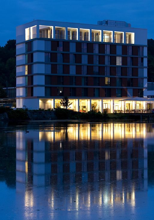 LAGO Hotel in Ulm, a stylish building with soft lighting reflected in the lake.