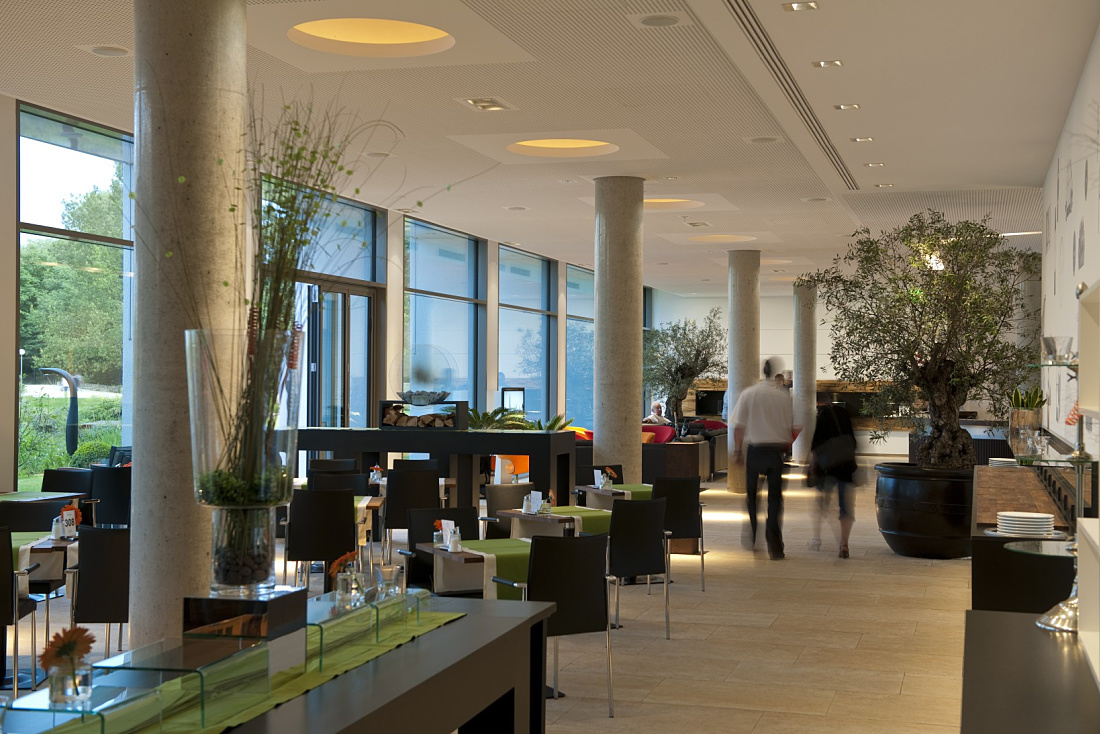 Bright, inviting hotel lobby at LAGO Hotel Ulm, featuring stylish lighting and plants.