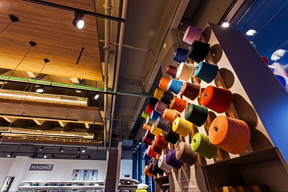 Decorative yarn spools wall in Ragno concept store, lit by ERCO Optec spotlights.