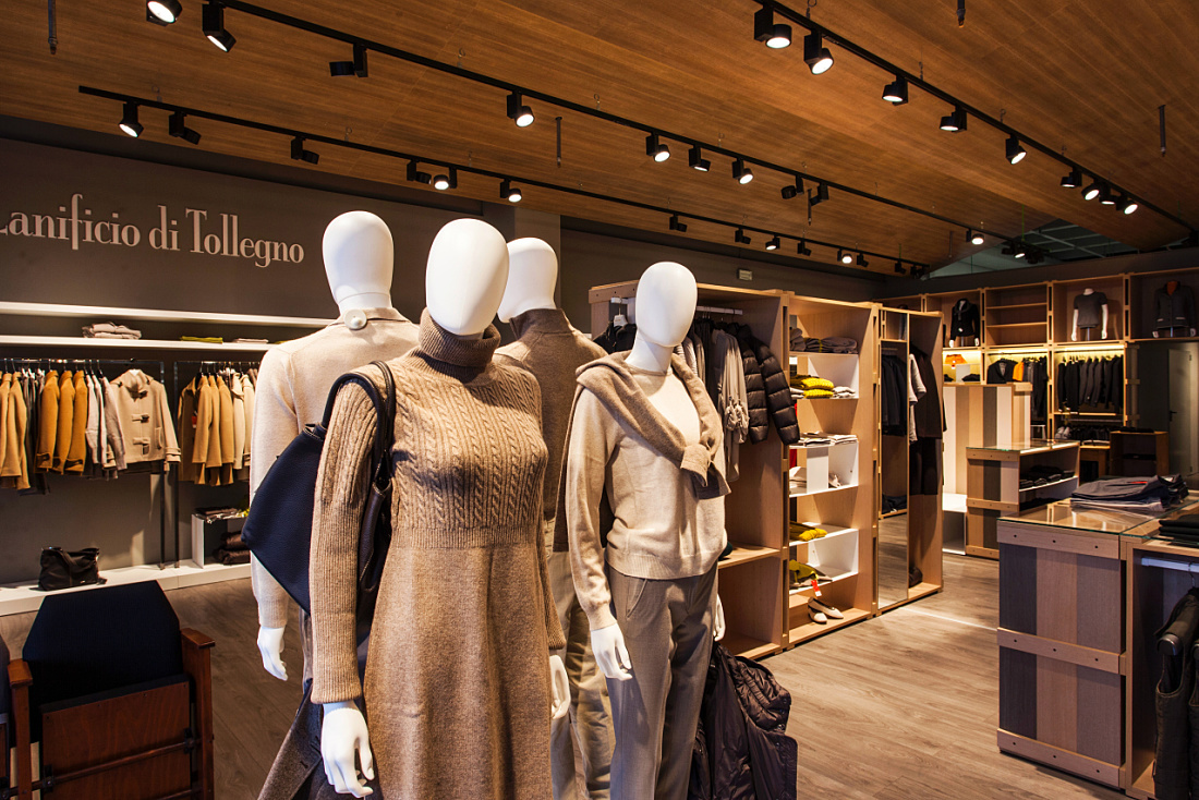 Lanificio di Tollegno store featuring mannequins with warm lighting accentuating high-quality fashion.