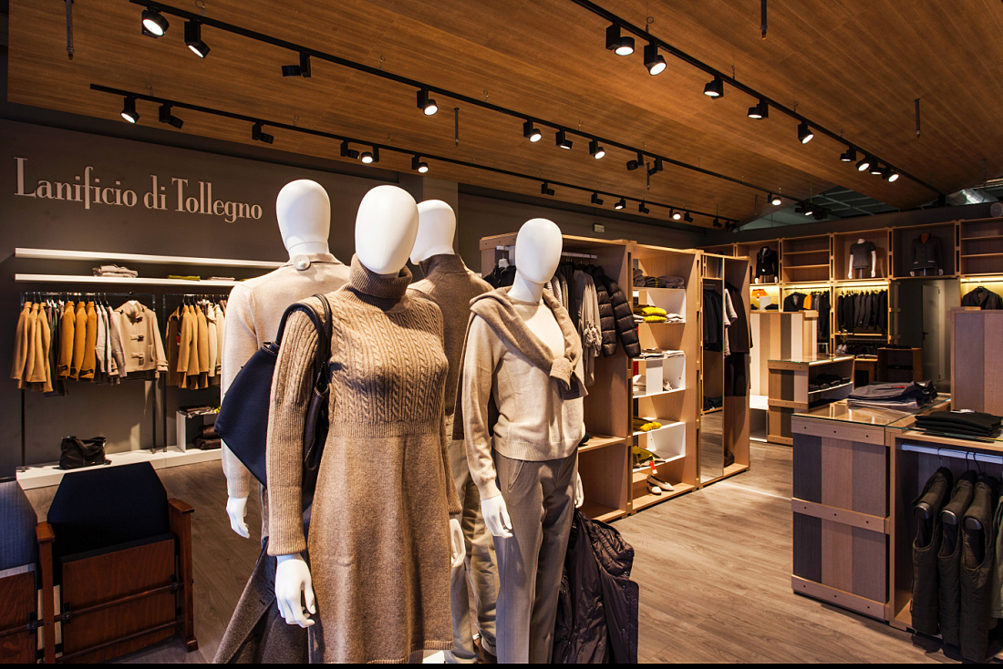 Lanificio di Tollegno store featuring mannequins with warm lighting accentuating high-quality fashion.