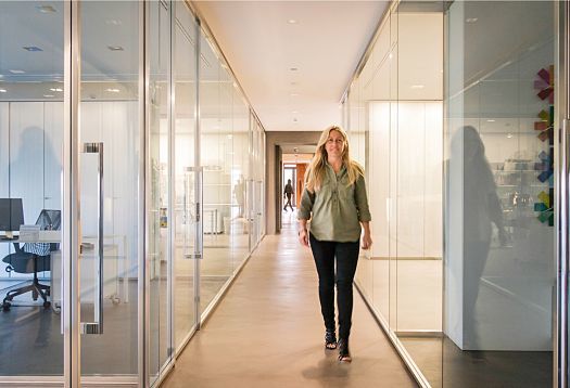 Woman walking in the Le Silla headquarters hallway, illuminated by ERCO recessed luminaires.