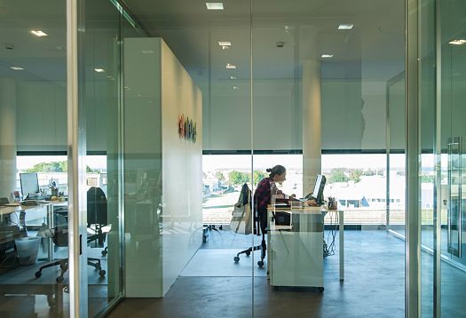 Le Silla office with ERCO lighting: Employee at desk in a modern, glass-walled office.