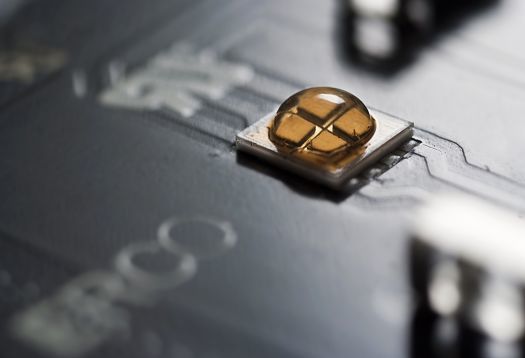 Close-up of an SMD LED on a circuit board, emitting light.