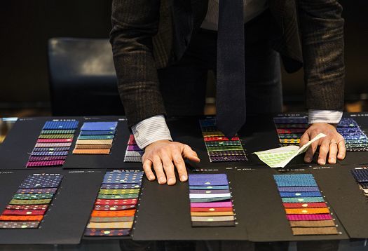 A man reviews fabric swatches, assessing color rendering for LED lighting applications.