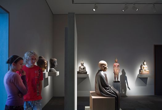 Visitors view Buddha statues in the Louvre-Lens, illuminated by ERCO LED lighting.