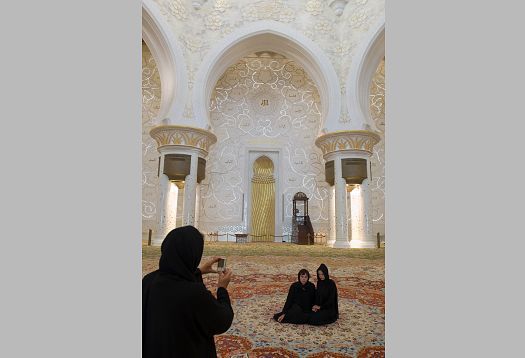 Women taking photos in Sheikh Zayed Mosque, illuminated by ERCO LED lighting.