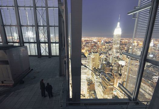 Empire State Building view at night through a modern window structure.