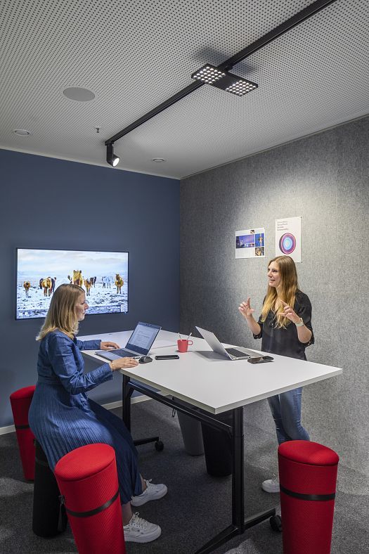 Flexible ERCO LED track lighting illuminates a co-working space with two people collaborating.