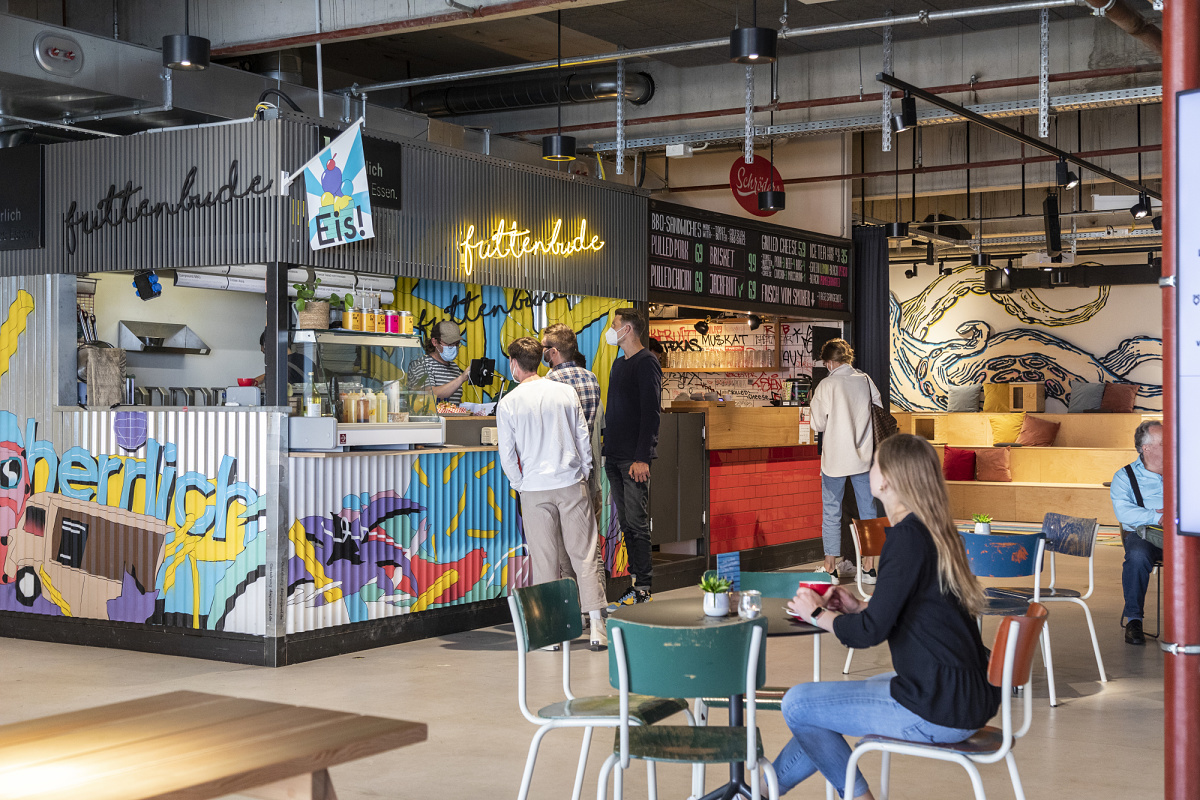 Bright ERCO LED downlights illuminate a flexible co-working space with food vendors.