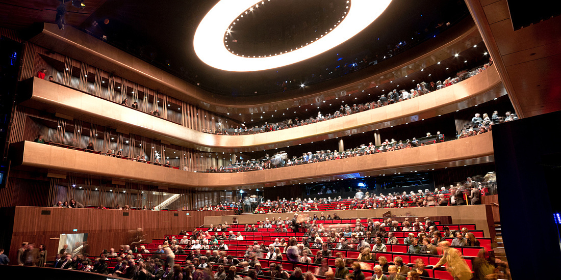 Interior of Linz Music Theater illuminated by ERCO lighting with an audience.
