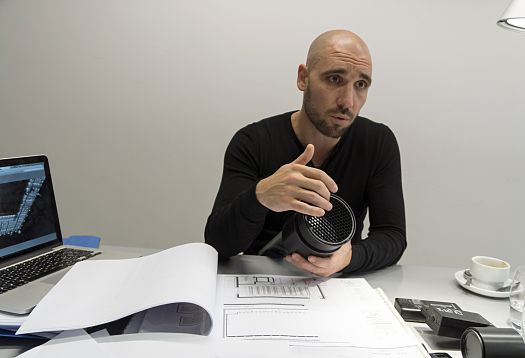 A man demonstrates an ERCO LED lighting tool, used in Louvre Abu Dhabi, with architectural plans.