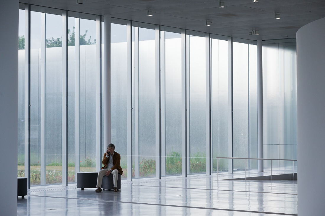 Man on phone in the bright Louvre Lens Museum, illuminated by ERCO LED lighting.