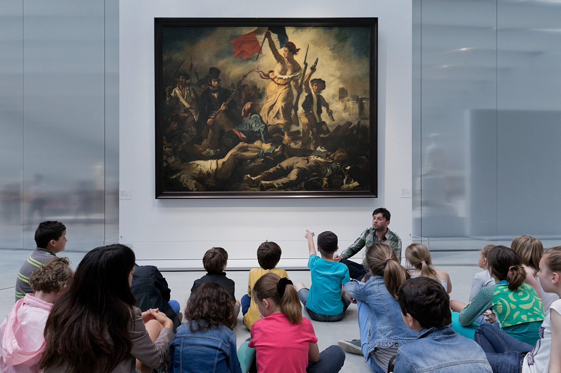 A group views Liberty Leading the People at the Louvre-Lens, illuminated by ERCO LED lighting.