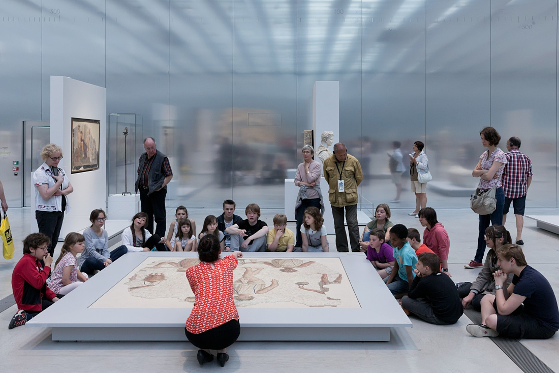 School group views a mosaic at the Louvre Lens Museum, illuminated by ERCO LED lighting.
