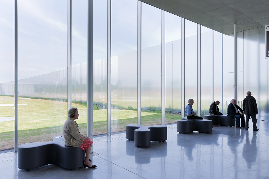 Visitors sit on benches in the Louvre Lens Museum, illuminated by ERCO LED lighting.
