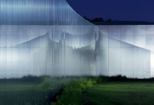 Louvre-Lens Museum facade at night, showcasing modern architecture and lighting.