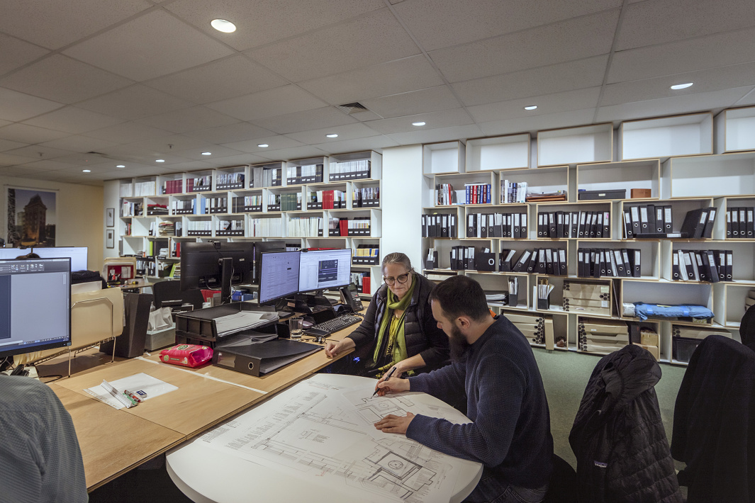 Lovell Chen Architektenbüro: Mitarbeiter besprechen Baupläne unter ERCO Downlights für Human Centric Lighting.