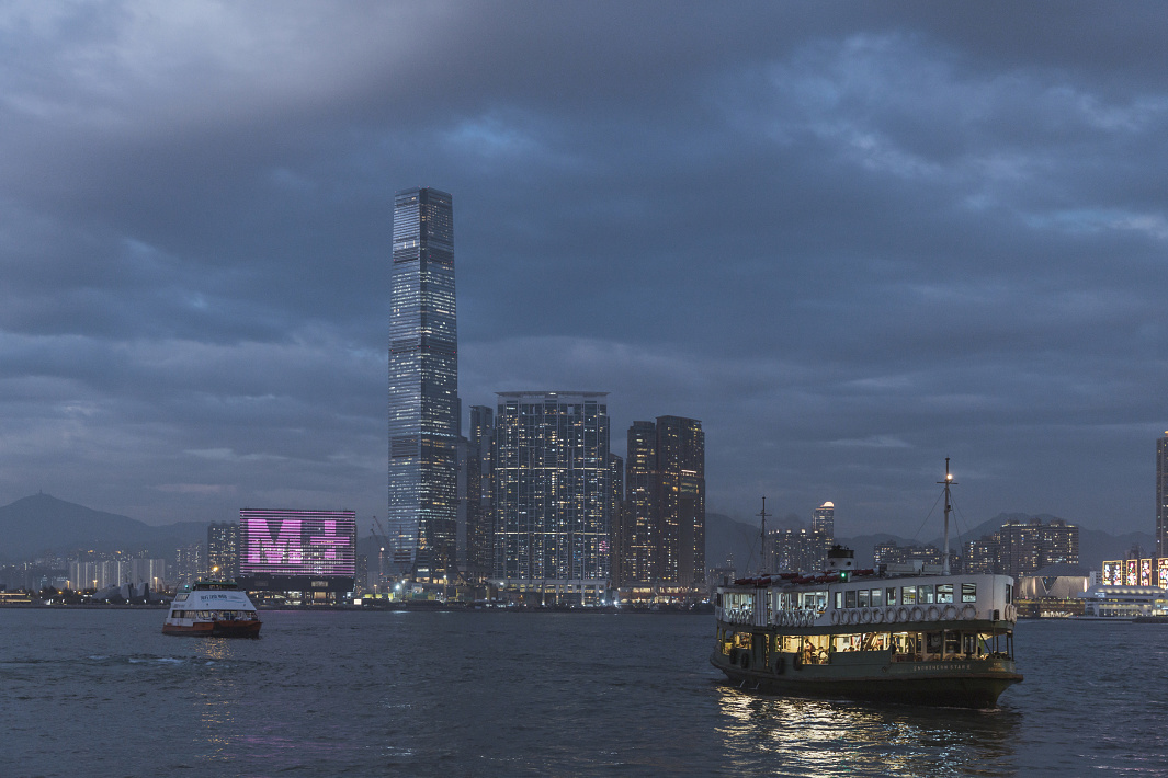 The M+ Museums illuminated facade in Hong Kong, viewed from the harbor.