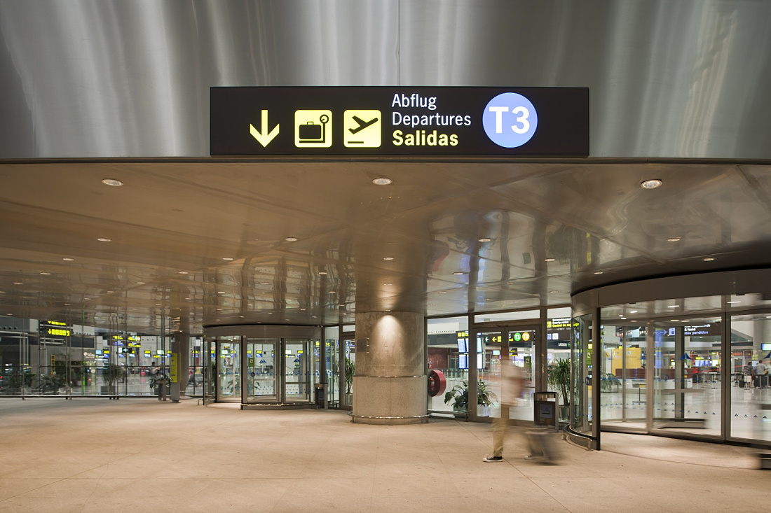 Malaga Airport Terminal 3: Signage for departures and baggage claim, lit by ERCO downlights.
