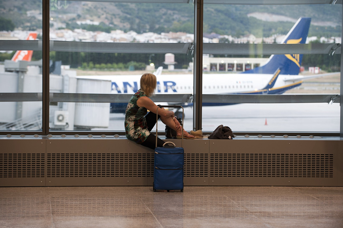Traveler waits at Malaga Airport Terminal 3 with ERCO lighting for their flight.