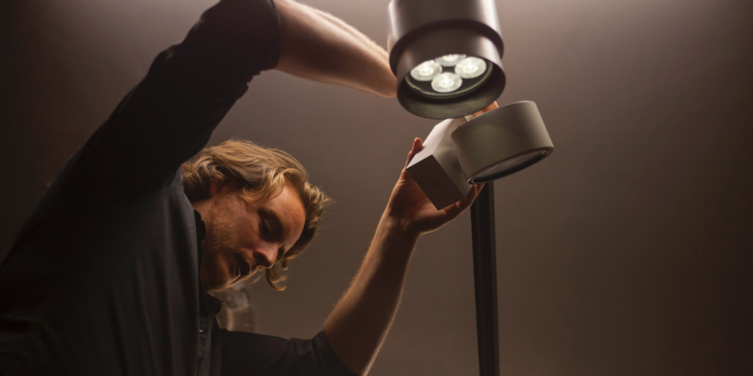 A man adjusts ERCO Pollux spotlights to enhance a Chiaroscuro-style painting.