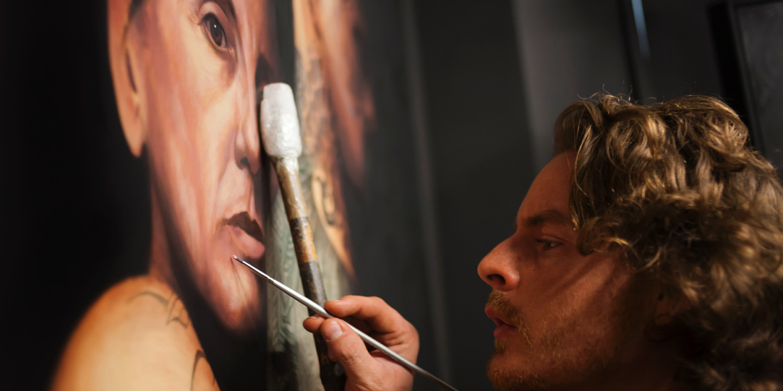Matthew Penn painting a hyper-realistic portrait in Chiaroscuro style, illuminated by ERCO spotlights in his studio.