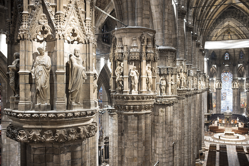 Interior of Milan Cathedral featuring sculptures on columns, illuminated by ERCO LED lighting.