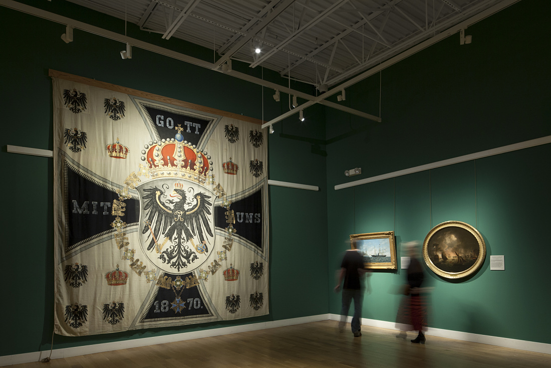 Minnesota Marine Art Museum exhibit featuring a Prussian war flag and paintings, illuminated by ERCO spotlights.