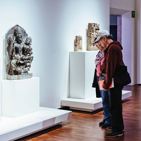 Visitors admire sculptures at Museu de Cultures del Món, illuminated by ERCO Optec spotlights.