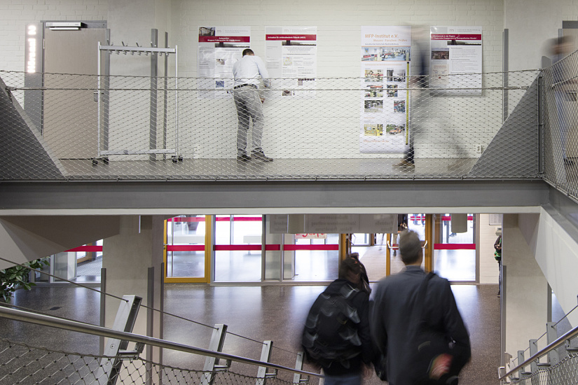 Interior view of Neubrandenburg University with people and signage.