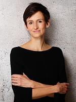 Portrait of Wiebke Lang, journalist for design, architecture and branding, against a gray wall.