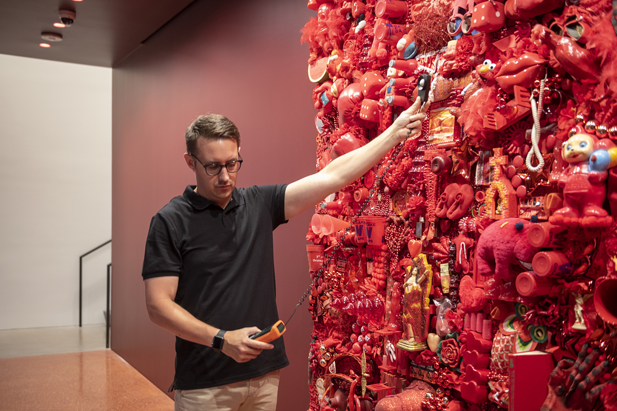 Lighting designer measures light levels on a red art installation with ERCO LED lighting at Ruby City Gallery.