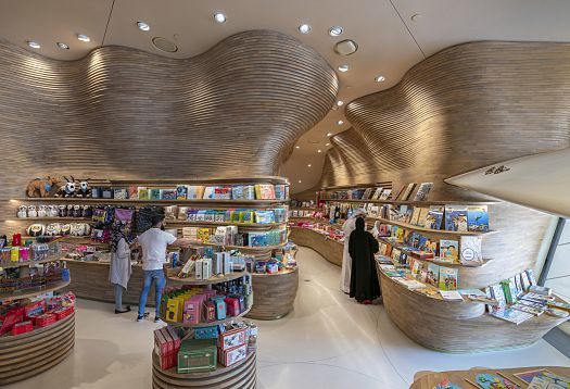 National Museum of Qatar gift shop featuring ERCO lighting and undulating wooden shelves.
