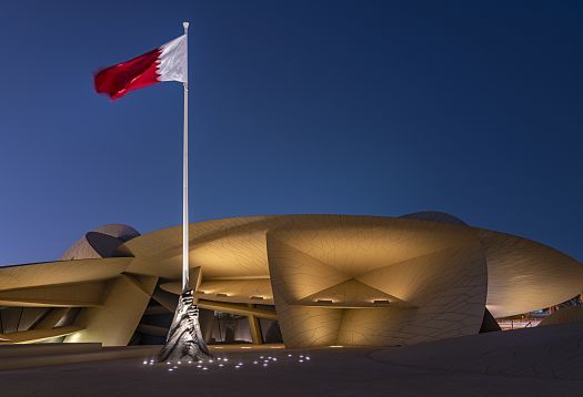 National Museum of Qatar illuminated by ERCO, featuring the Qatari flag.