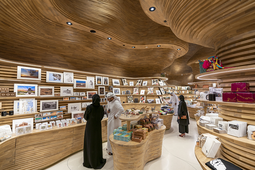 National Museum of Qatar gift shop with ERCO lighting and undulating wooden shelves.