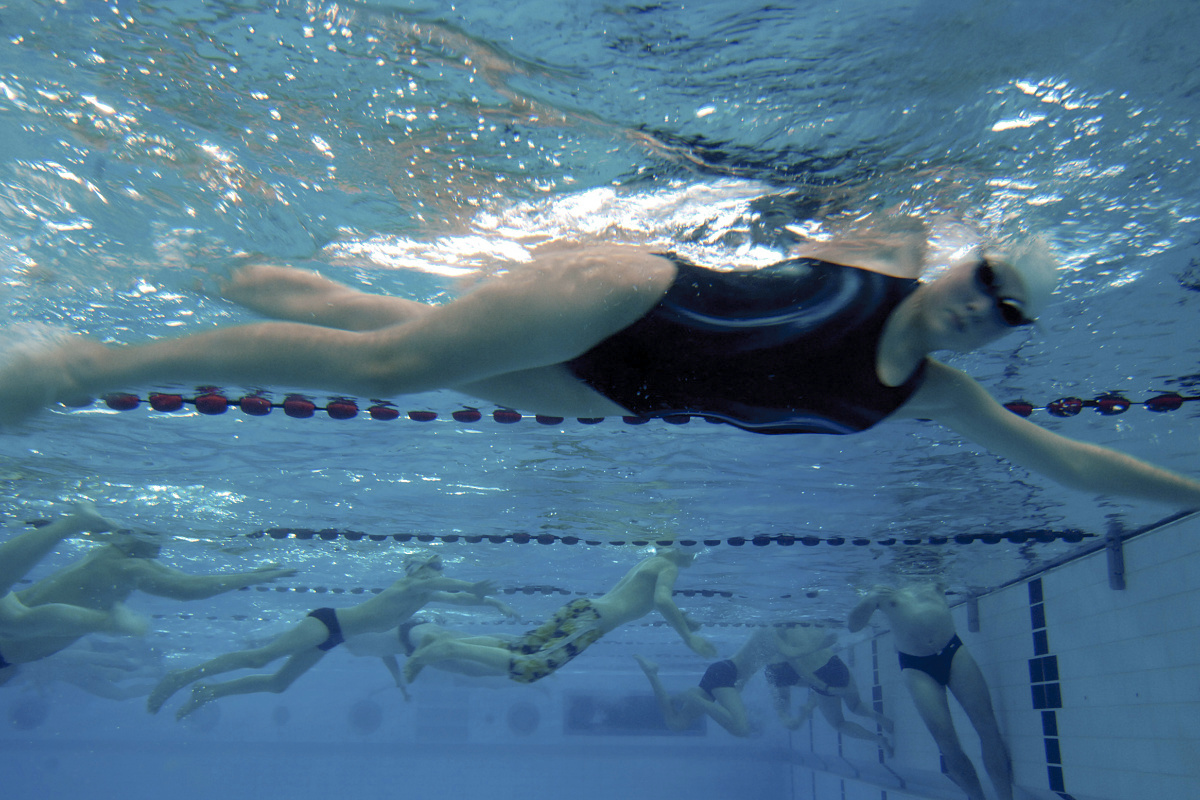Underwater view of swimmers in the Olympia Schwimmhalle, illuminated by ERCO Focalflood floodlights.