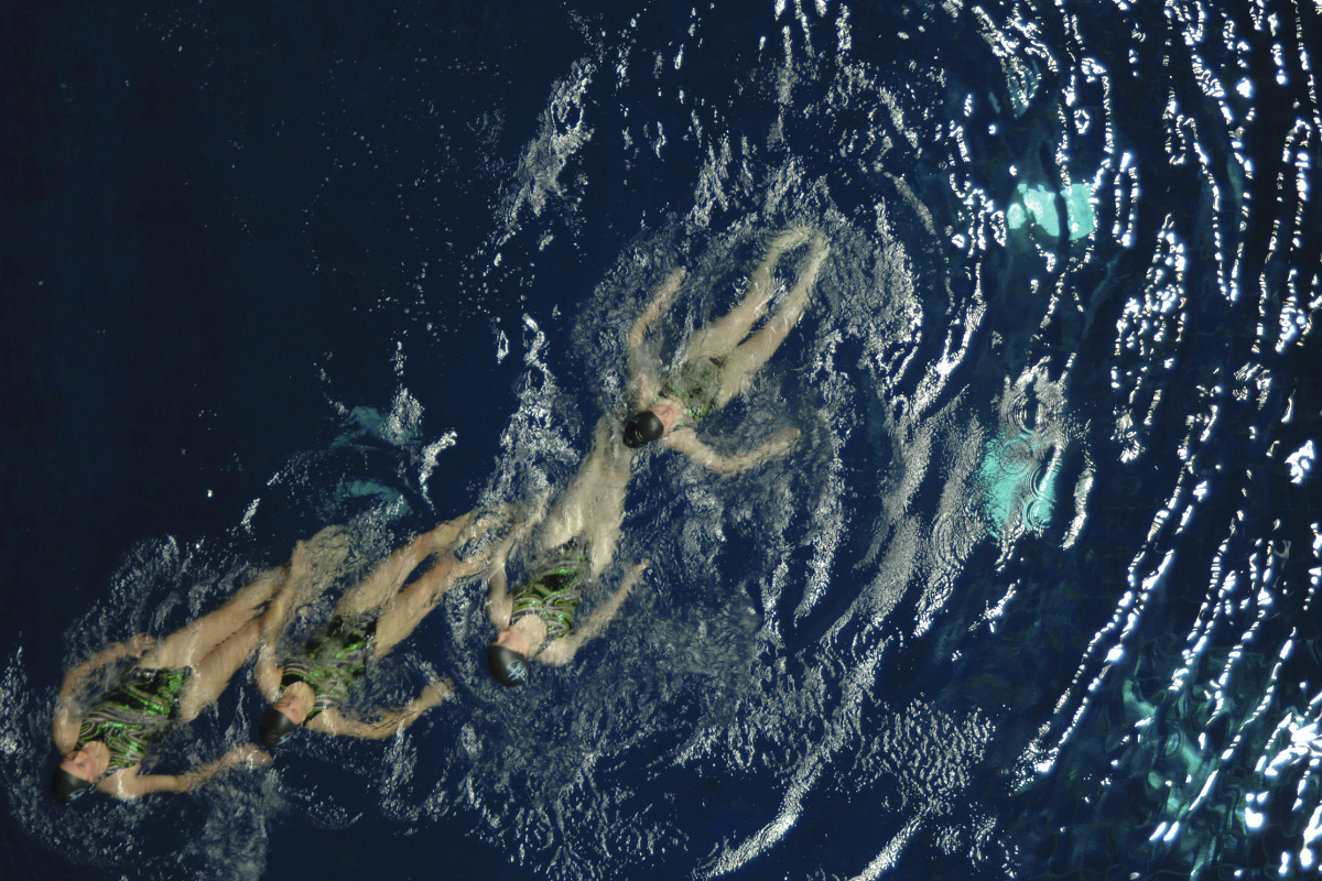 Synchronized swimmers in Munichs Olympic swimming hall, illuminated by ERCO Focalflood projectors for competitions.
