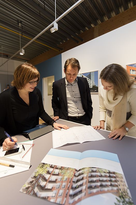 Otto Wulff project team reviews building plans in showroom, lit by ERCO LEDs for optimal color rendering.