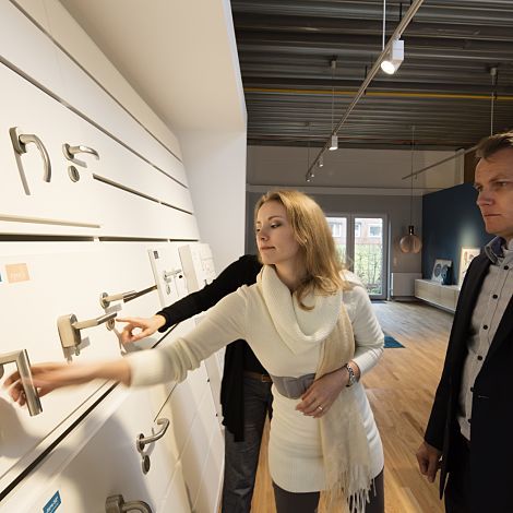 Customers selecting door hardware in the Otto Wulff showroom, lit by ERCO LEDs for optimal color rendering.